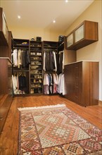 Walk-in closet with assorted men's and women's clothes and carpet in extension inside luxurious log