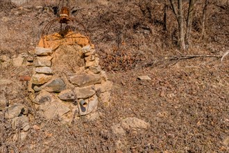 Stone structure with rusted wire frame and pipe sticking out of bottom in mountain park in Boeun,