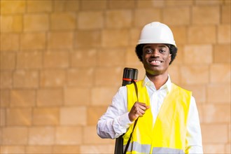 Portrait of a young african architect with protective hard hat and reflective waistcoat in a