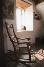 Antique wooden rocking chair in master bedroom on upstairs floor inside old 1785 home, Quebec,