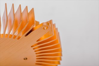 Closeup of fins and mounting flange on round copper computer heat sink on white background