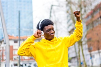 Stylish african young man dancing while listening to music with headphones in the city