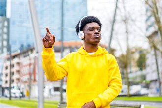 African young man in yellow clothes dancing listening to music in the city street