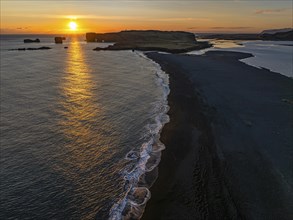 Sunset over the rocks of Dyrholaey, drone shot, Sudurland, Iceland, Europe
