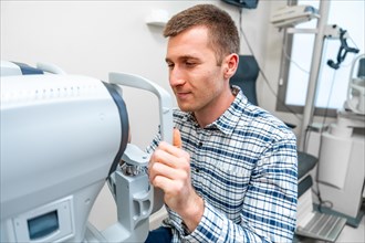Man holding the handles of a eye scanner in an ophthalmology clinic