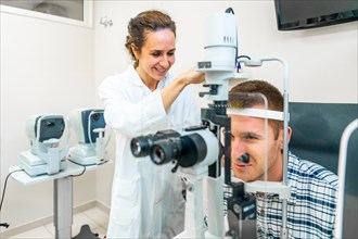 Young man at the optometrist getting his eyes checked by a female doctor