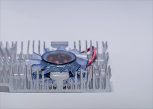 Closeup of aluminum heat sink and blue plastic fan assembly on white background