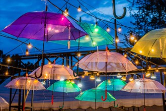 Colorful umbrellas with lights hang artistically against a dusk sky, in Chiang Mai, Thailand, Asia