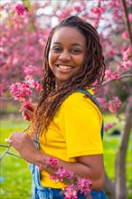 Vertical portrait of a young african woman next to pink floral tree