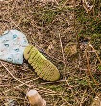 Discarded shoe amidst plastic litter on the ground, showing environmental damage, in South Korea