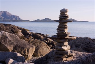Balanced pile of stones on a quiet coastal landscape with a mountain panorama in the background
