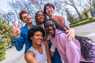 Frontal three quarter length portrait of five cute young multiracial friends talking selfie in a