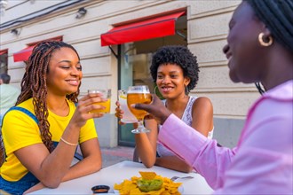 African women toasting on an outdoor terrace while eating fast food and nachos
