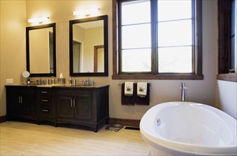 Wooden vanities and freestanding oval bathtub in main bathroom in extension inside luxurious log