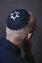 Jewish man wearing a kippa with a Star of David on his head, back view, studio shot, Germany,