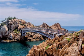 A bridge spanning over rocks by the sea with a clear blue sky, in Ulsan, South Korea, Asia