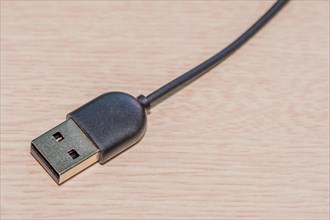 USB charging cord on wood grain background