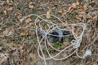 Old shoes tied with a rope lying on leaf-strewn ground, in South Korea