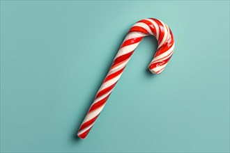Top view of single red and white striped Candy Cane on blue background. KI generiert, generiert, AI