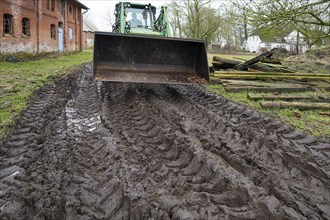 Tractor with tyre tracks on soaked ground on a farm, Othenstorf, Mecklenburg-Vorpommern, Germany,