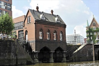 Historic brick house on the banks of a river with reflections in the water, Hamburg, Hanseatic City
