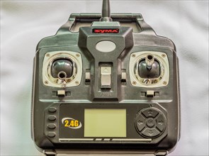 A SYMA branded black remote control with joysticks and a digital display, in South Korea
