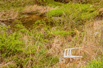 An abandoned plastic chair by a stream highlights a pollution issue, in South Korea