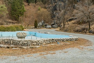 Empty water fountain with large concrete ornamental center piece in mountainside public park in