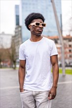 Vertical photo of a handsome african cool man in summer white clothes in the city