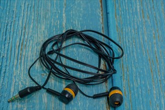 Set of black and yellow used ear buds on blue wood grain background