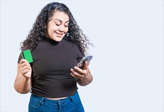 Happy girl holding credit card shopping online with phone isolated. Person making online purchases