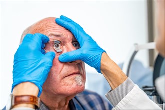 Ophthalmologist applying an eye opener on a senior patient before an innovative treatment for
