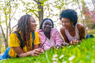 Three female african young friends lying on a park talking relaxed enjoying spring day