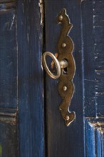 Antique metal plate and key on blue painted antique wooden armoire in bedroom inside old 1877 home,