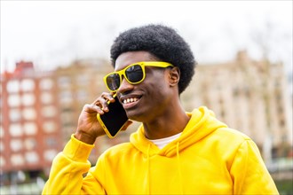Cool stylish young african man talking to the mobile phone standing outdoors in a city