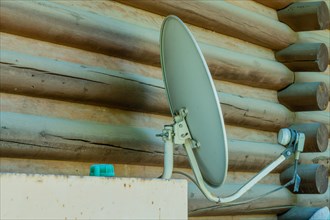 Satellite television receiver dish mounted on exterior wall of log cabin in South Korea