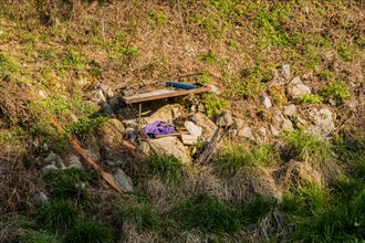 Discarded items and garbage strewn across an outdoor area with grass and rocks, in South Korea