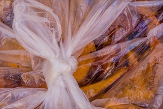 Macro shot of a tied plastic bag revealing the textures of trapped fall leaves, in South Korea