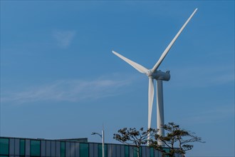 Close up of wind turbine blades above a building with blue sky in background in South Korea