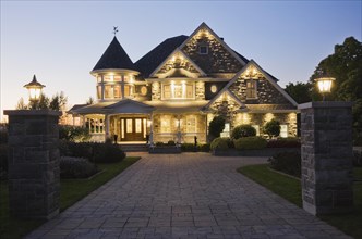 Elegant grey stone with white trim and blue asphalt shingles roof Victorian home facade at dusk in
