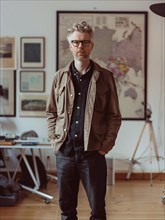 A casually dressed man with glasses standing confidently in his creative workspace, AI generated