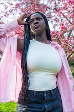 Vertical low angle view portrait of an african model posing next to flowering pink tree