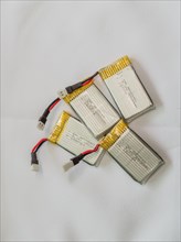 Several lithium polymer batteries with connectors and yellow tape on a white surface, in South