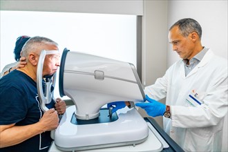 Senior man during a glaucoma inspection with a scanner on the pupil in a clinic
