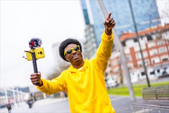 African cool young vlogger pointing ahead during a live streaming in the city