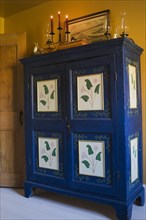 Antique blue and green painted wooden armoire in bedroom on upper floor inside old 1877 home,