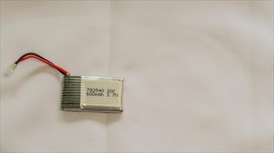 A lithium polymer battery with a label and wires on a white surface, in South Korea