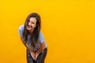 Studio portrait with yellow background of a casual woman laughing at camera