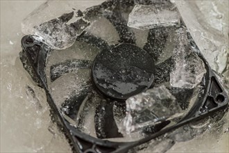 Closeup of computer case fan frozen in block of ice. Concept keep your computer cool