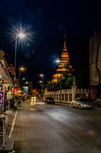 Quiet city street at night with temple in the background under a clear sky, in Chiang Mai,